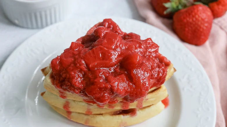 Simple Strawberry Compote atop three small waffles on a fancy white plate