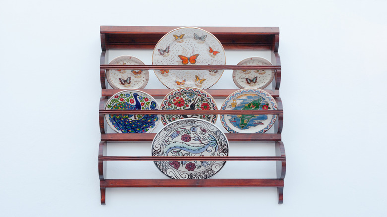 A vintage wooden plate rack hanging on the wall, holding decorative, colorful plates