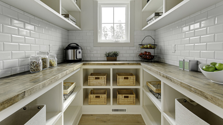 A bright, well-organized pantry featuring different glass storage jars, baskets, and bins