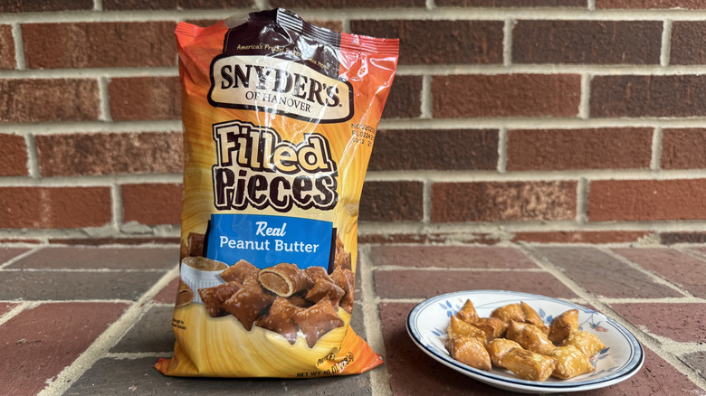Bag of Snyder's of Hanover peanut butter-filled pretzels on brick surface, with some displayed on adjacent plate