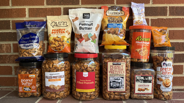 13 packages of peanut butter-filled pretzels from different brands, stacked against brick wall