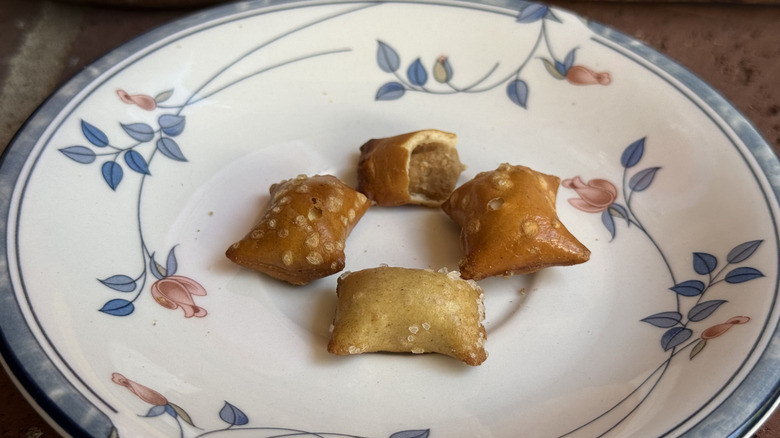 Four peanut butter-filled pretzel nuggets from different brands on plate