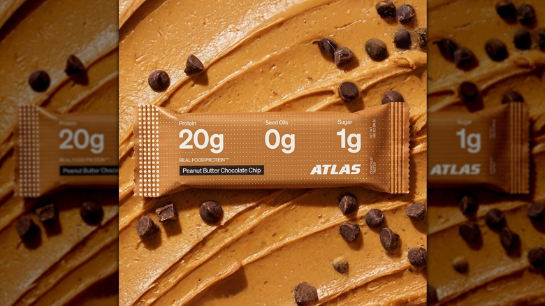 Atlas peanut butter protein bar with peanut butter swirls in the background