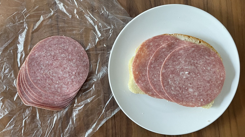 Genoa Salami on a plastic sheet and an open sandwich