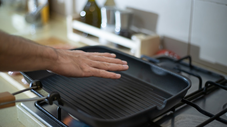 Person feeling to see if pan is preheating