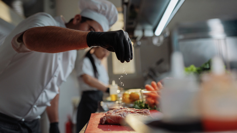 Chef seasoning meat in the kitchen