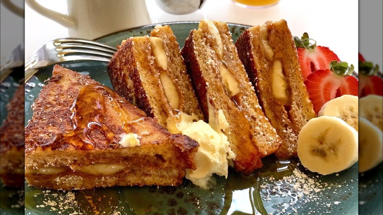 Order of peanut butter- and banana-stuffed French toast with a fork on a blue-green plate