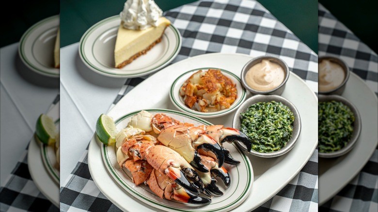 Crab claws, sides, and a slice of pie on a checkered tablecloth
