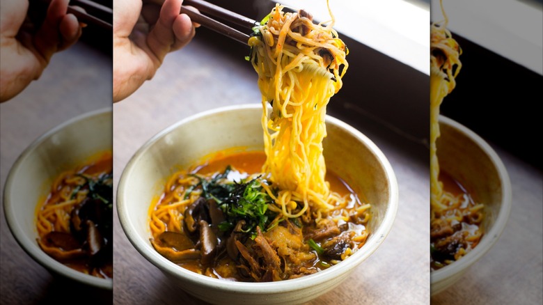 Dish of ramen with noodles being picked up with chopsticks