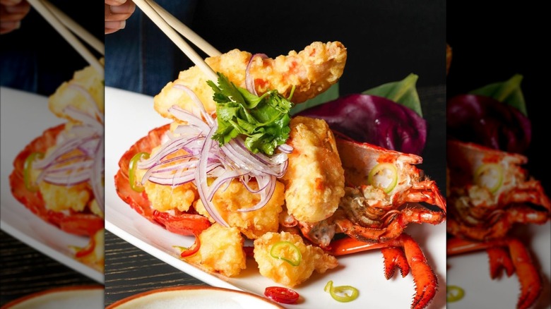 Plate of lobster tempura with one piece being picked up with chopsticks