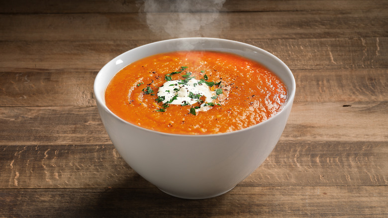 Steaming bowl of tomato soup with cream 