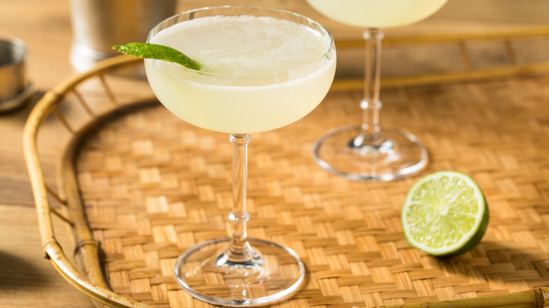 A daiquiri in a coupe on a woven tray with half a lime
