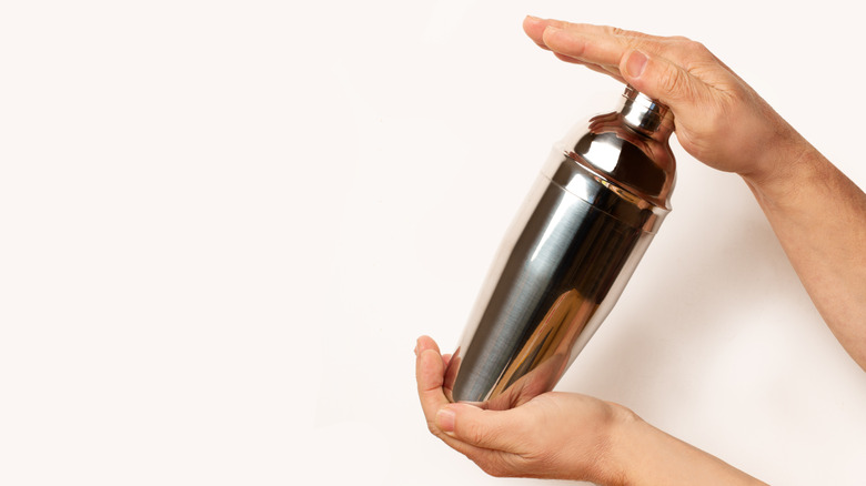 Two hands holding a closed cocktail shaker