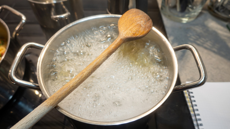 Pasta boiling in pot of water with wooden spoon