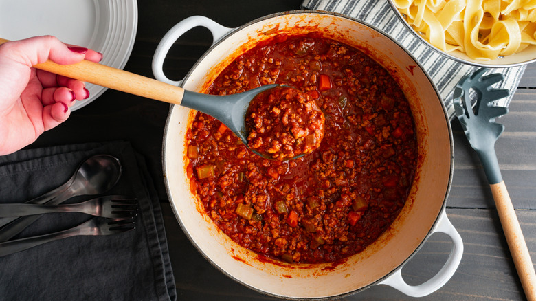 Bolognese sauce in Dutch oven with spoon