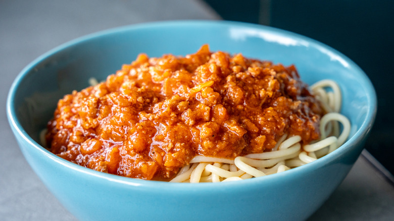 Meat sauce on bed of spaghetti in blue bowl