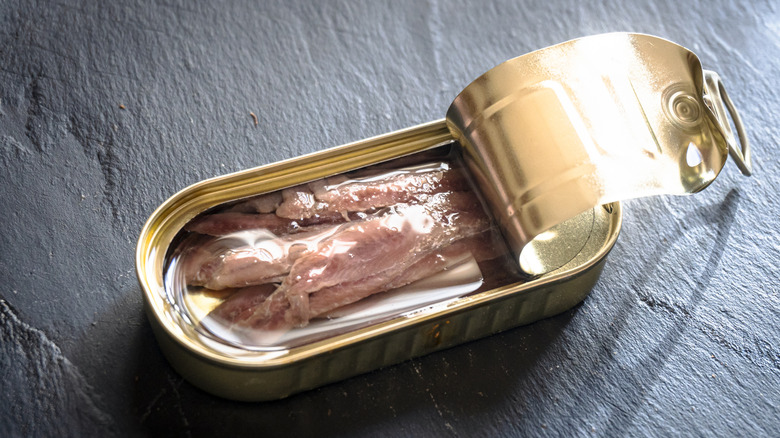 Open can of anchovies on table