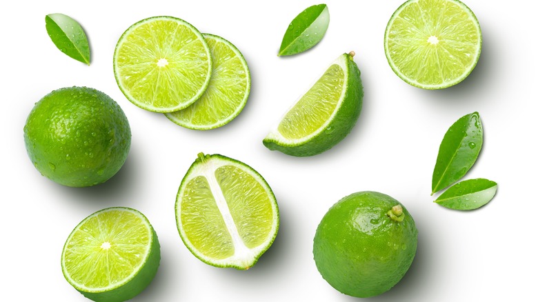 Whole and sliced limes on white background 