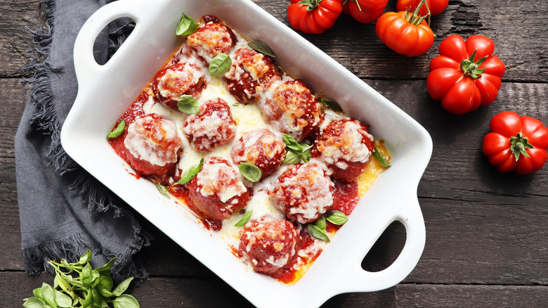 Meatball casserole in white baking dish with herbs