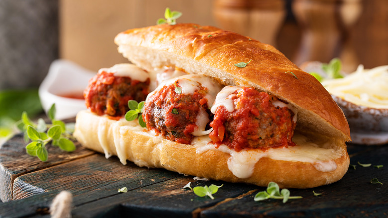 Meatball sub on wooden table with herbs