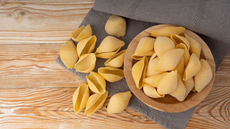 Jumbo pasta shells in wooden bowl on grey towel