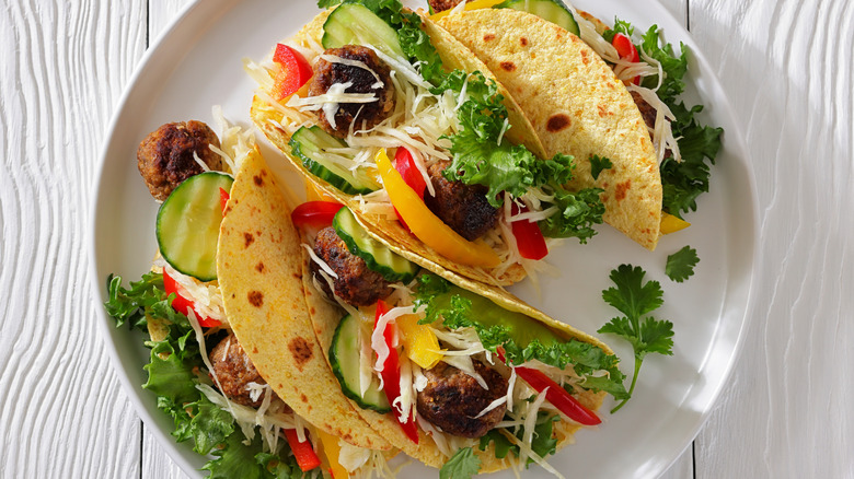 Meatball tacos with colorful vegetables on white plate