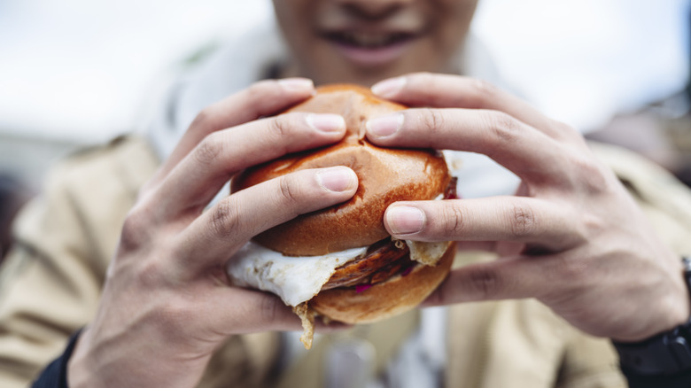 Person holding a breakfast sandwich they're about to eat