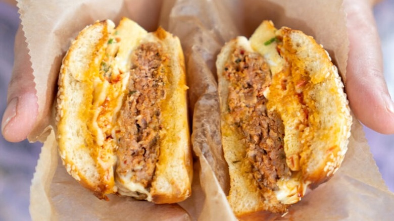Hands holding an OG breakfast sandwich that has been sliced in half
