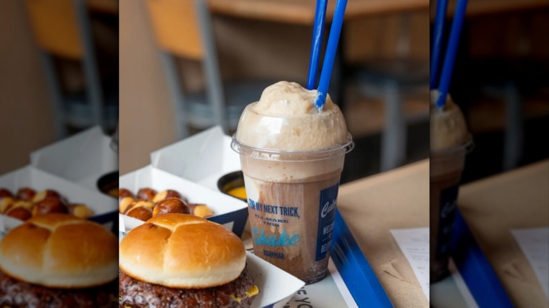 A foamy cup of root beer with straw