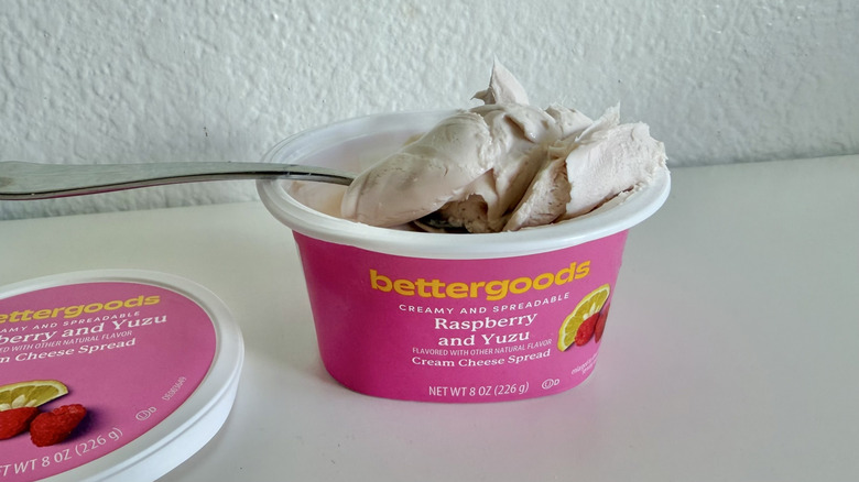 Container of Better Goods Raspberry Yuzu Cream Cheese Spread with a spoon on top of the container