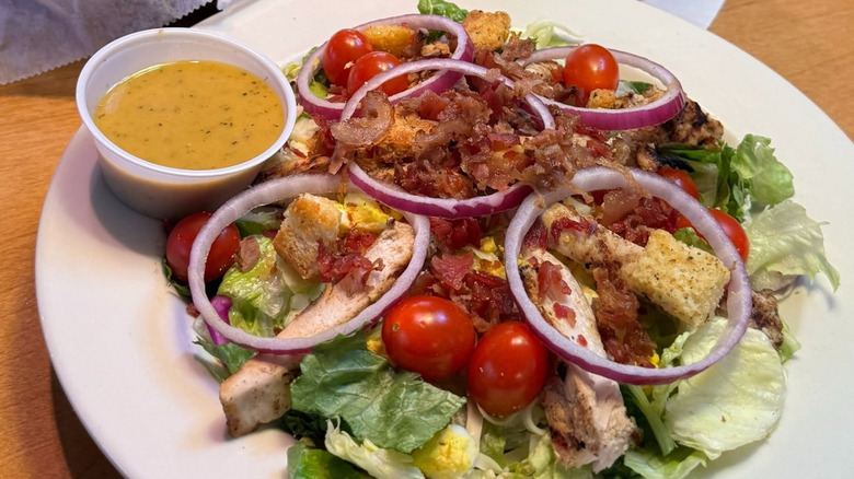 Grilled chicken salad at Texas Roadhouse on a white plate with dressing on the side