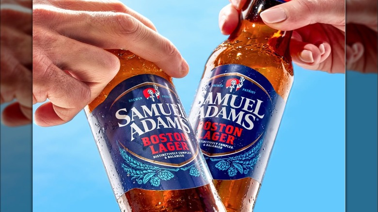 Two hands holding bottles of Sam Adams and clinking them together