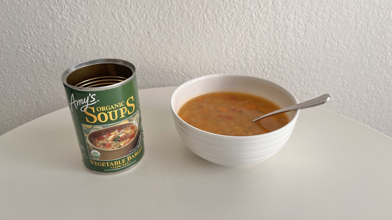 Open can of vegetable barley soup with a bowl