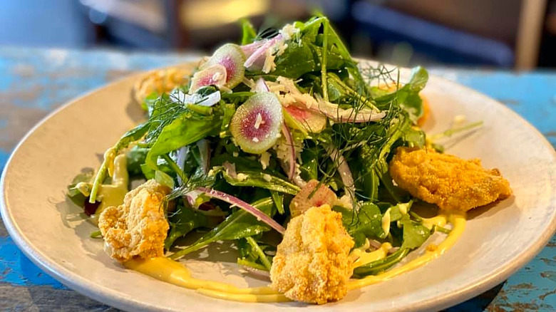 Fried oyster, arugula, and fig salad from Pêche Seafood Grill on a white plate