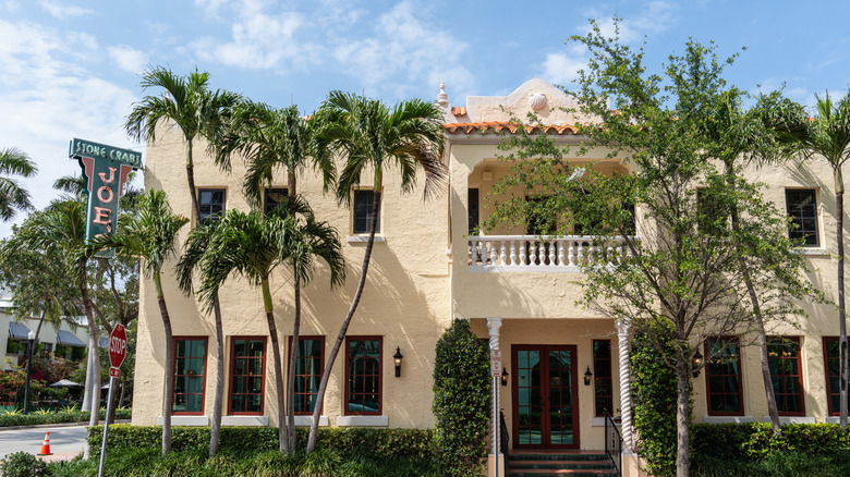 Exterior shot of Joe's Stone Crab with palm trees during the daytime