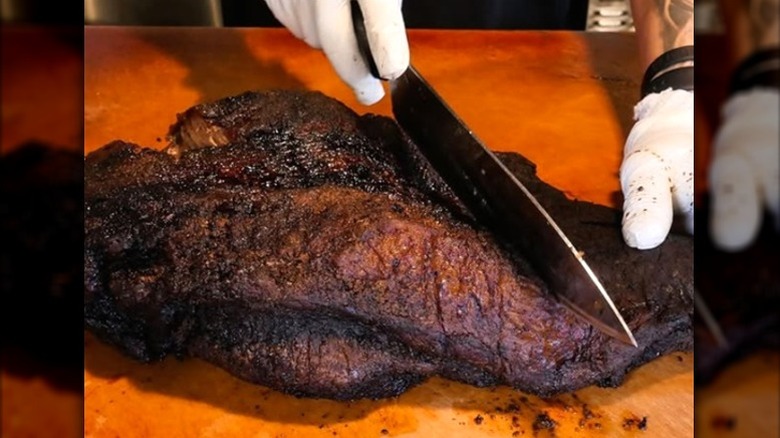 large knife slicing a smoked barbecue brisket