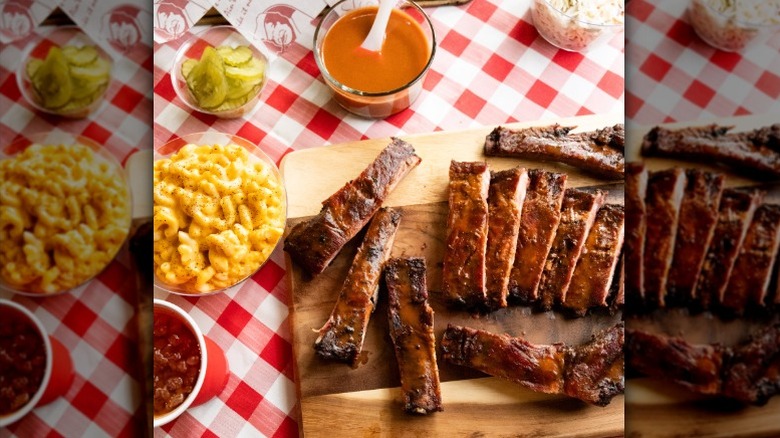 cutting board with sliced barbecued meat and sides on table