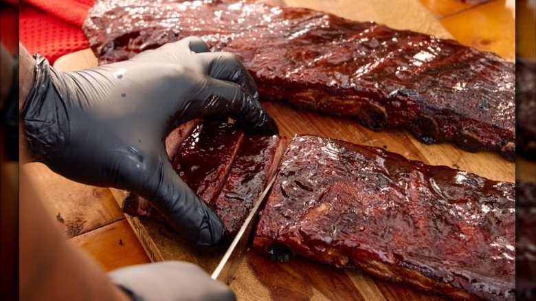 close up of hand slicing barbecue ribs