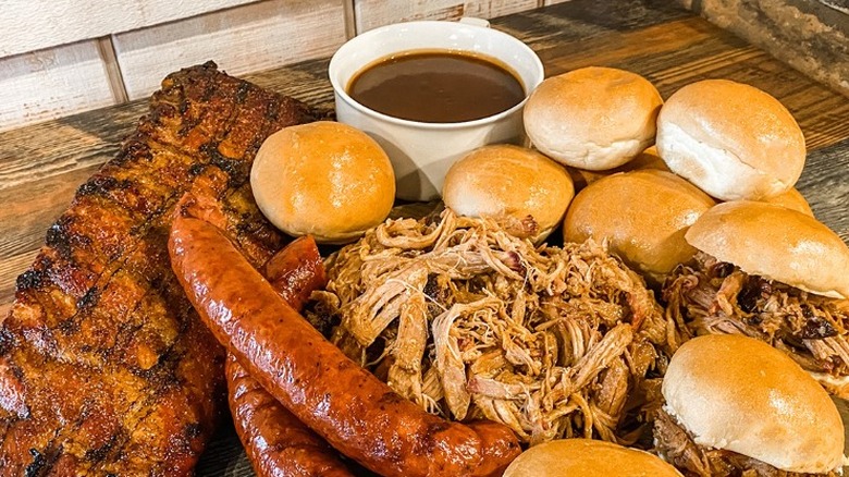 close up of barbecue meats and sandwiches with cup of sauce