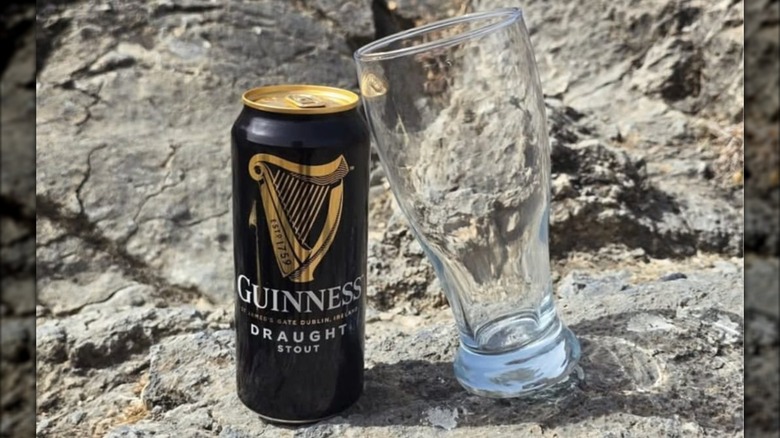 Can of Guinness Draught and pint glass on a rock