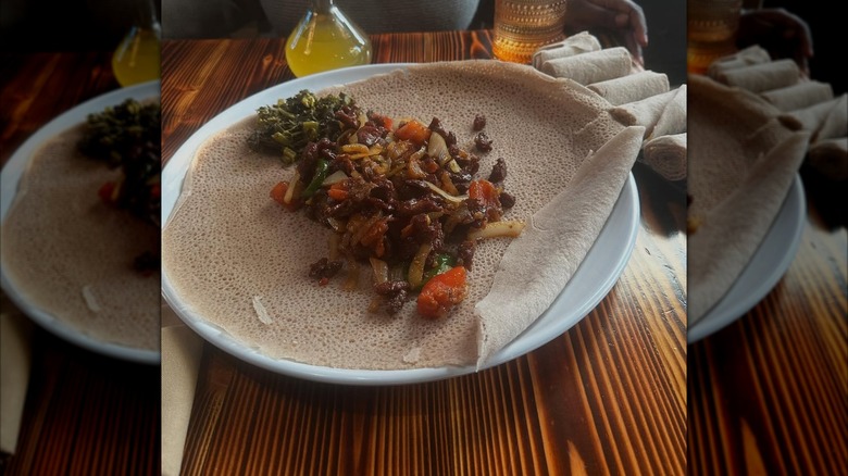 Injera platter with assorted meat and vegetable pairings on top