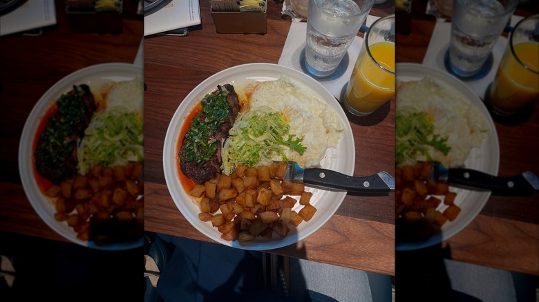 Home fries, steak, and fried eggs platter, with glass of orange juice
