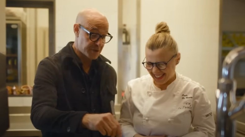 Stanley Tucci standng in a kitchen with a chef