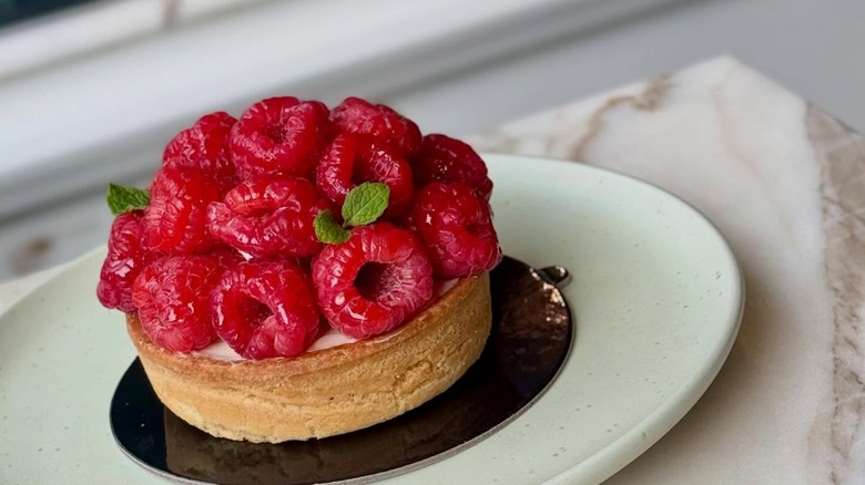 Pastry with raspberries on plate on marble table
