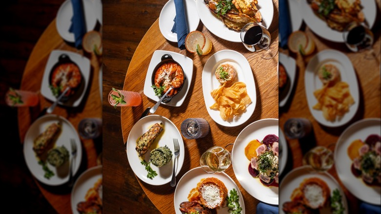 Elegant dishes on white plates and cocktails on a rustic wood table