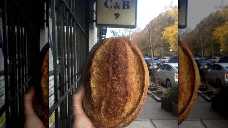 A person holding sourdough loaf outside of C&B in New York City
