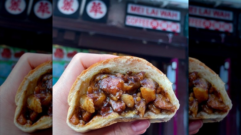 A person holding a pork bun outside of Mei Lai Wah