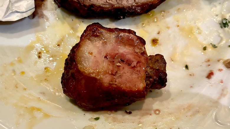 Bacon-wrapped steak on white plate at Fogo de Chão