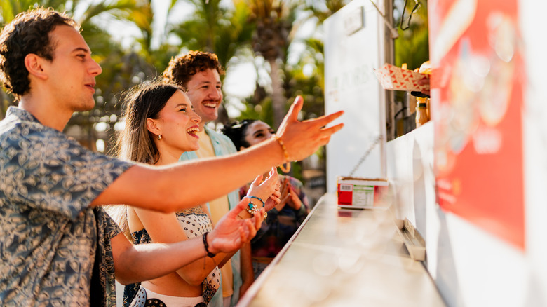 Group of people standing by a food truck in the sun