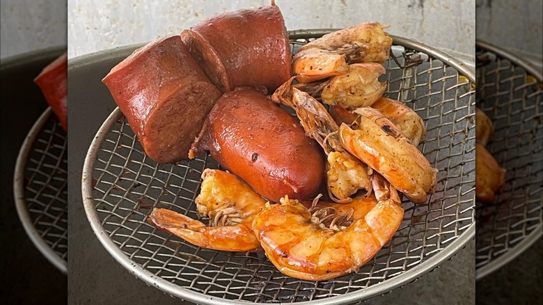 Shrimp and sausage pieces on strainer